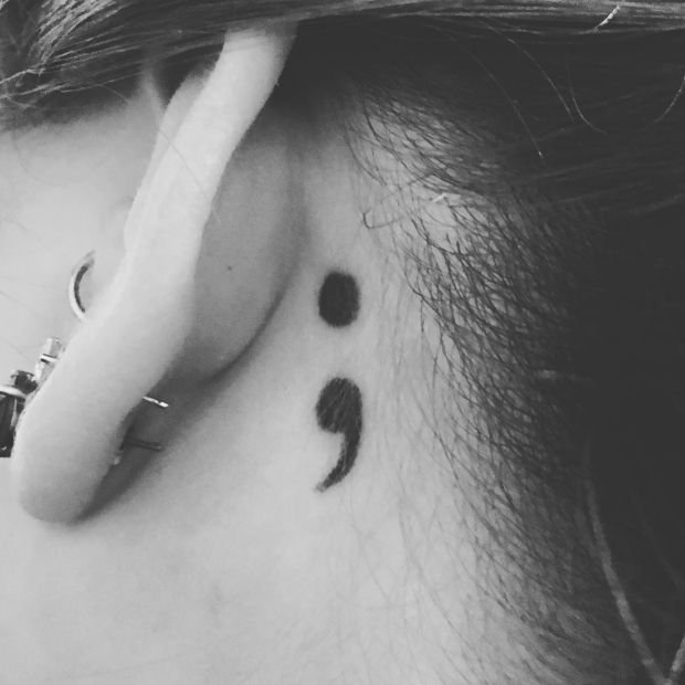 Semicolon tattoo behind the left ear