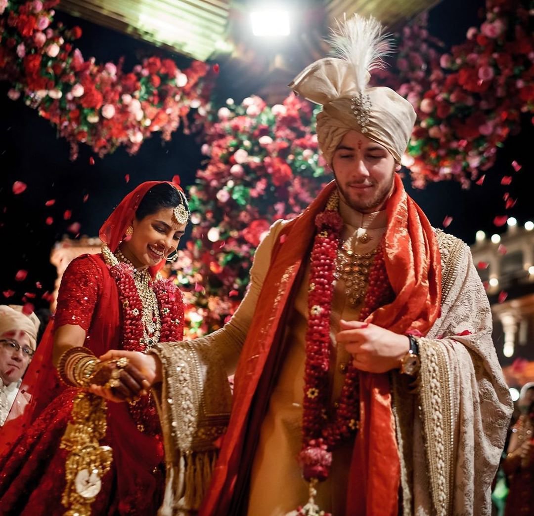 The quintessential red lehenga that's become synonymous with bridal attire,  makes its way into the cross-cultural wedding ceremony of our... | Instagram