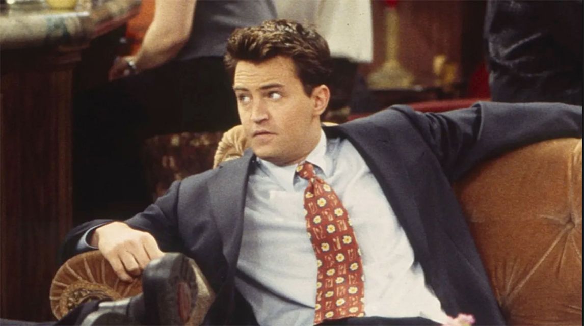 Matthew Perry lounging on the Friends' couch, looking concerned
