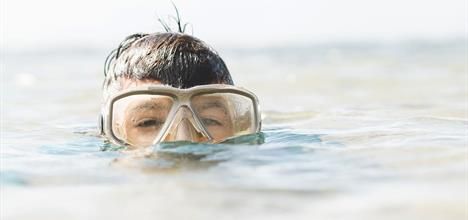 A swimmer in goggles above water: nose clips FTW