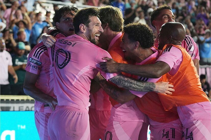 Messi celebrating with teammates and substitutes in a pink pile-on